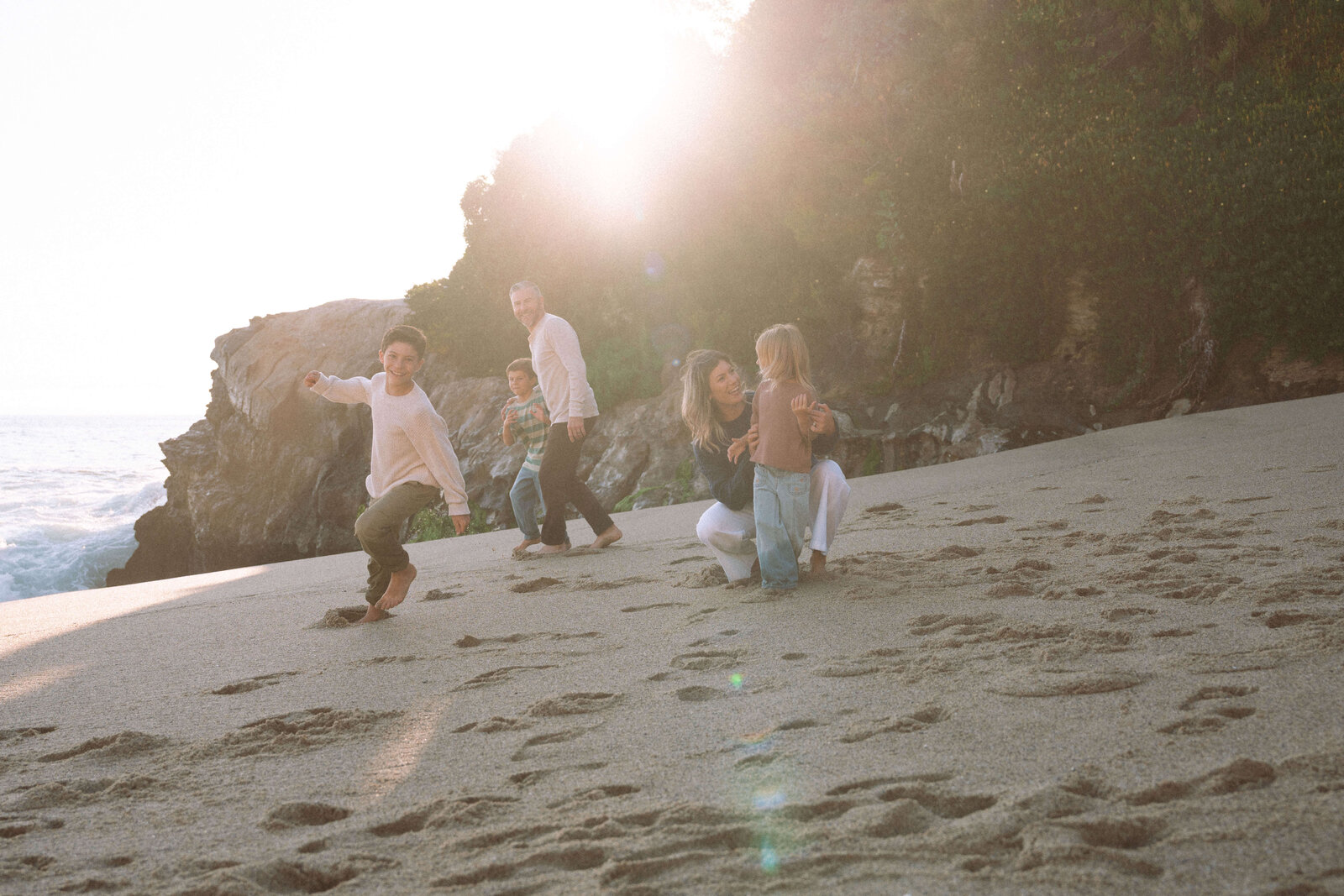 Candid moment of family running and playing on the beach at sunset in Laguna Beach, CA