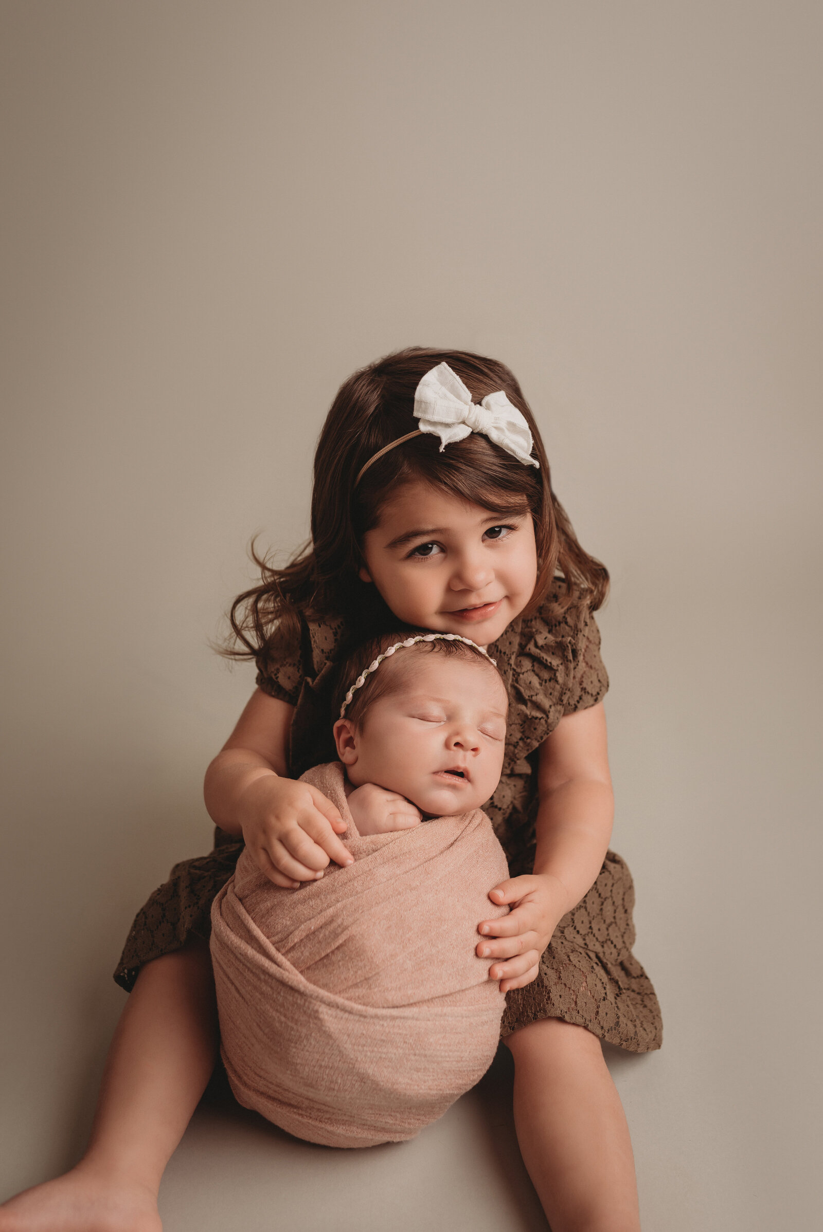 Newborn picture of baby and big sister in pink and brown