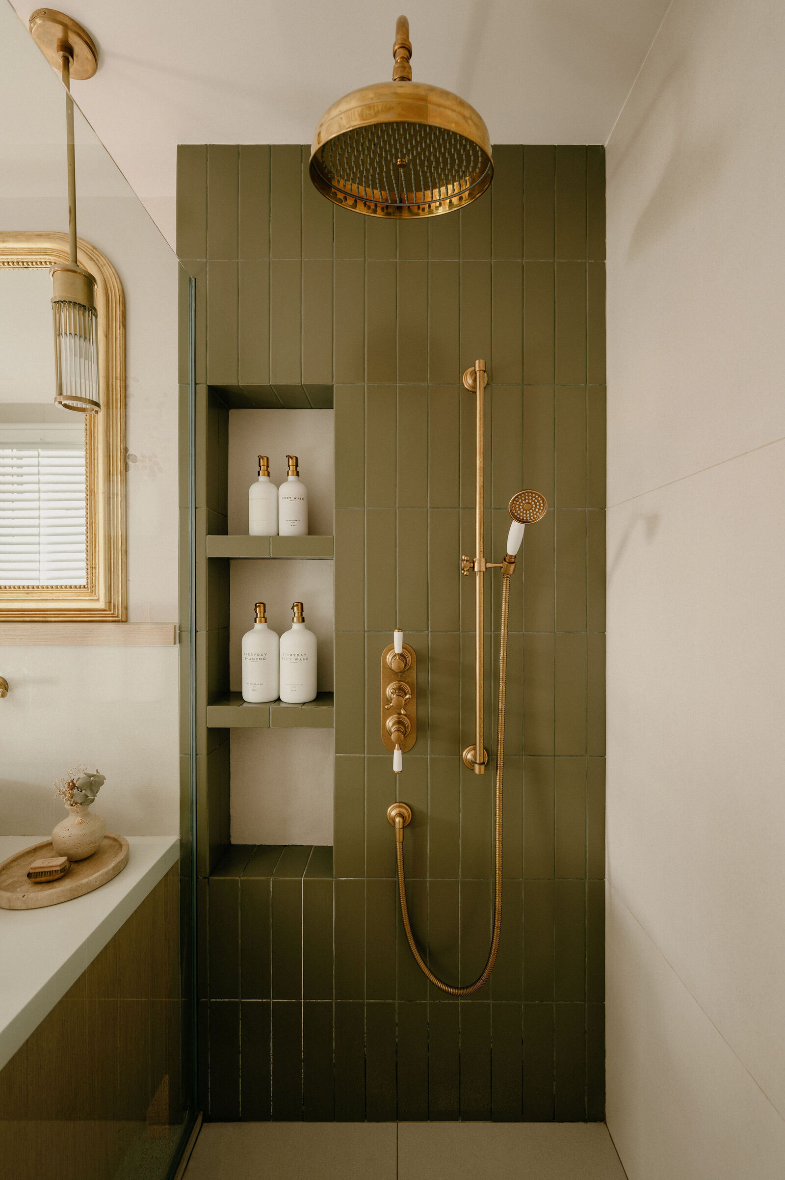 Green, ceramic tiled bathroom with brass details, brass showerhead 