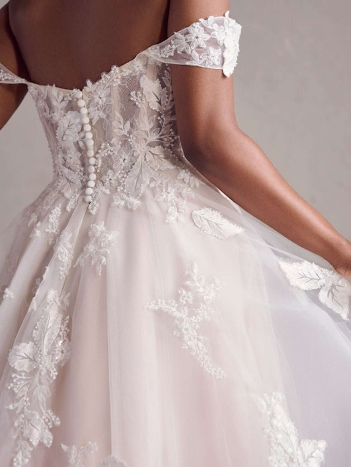 Back view of an off-the-shoulder lace wedding gown with button detailing