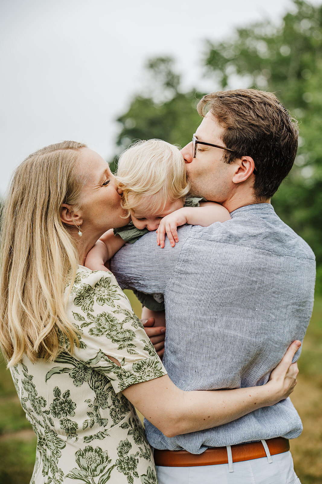 mom and dad kiss top of baby's head during first birthday photos in boston