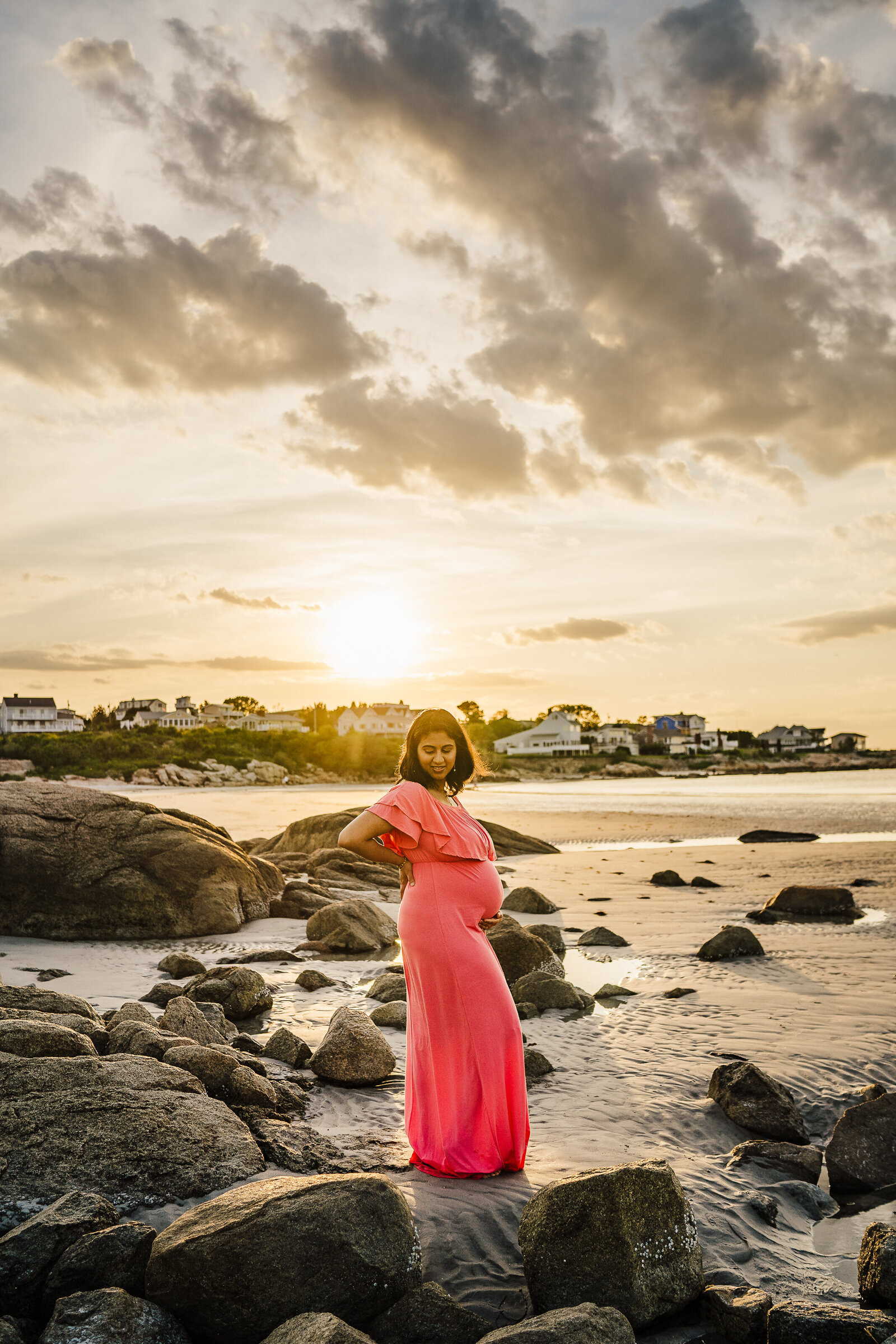 pregnant woman in pink dress on beach at sunset