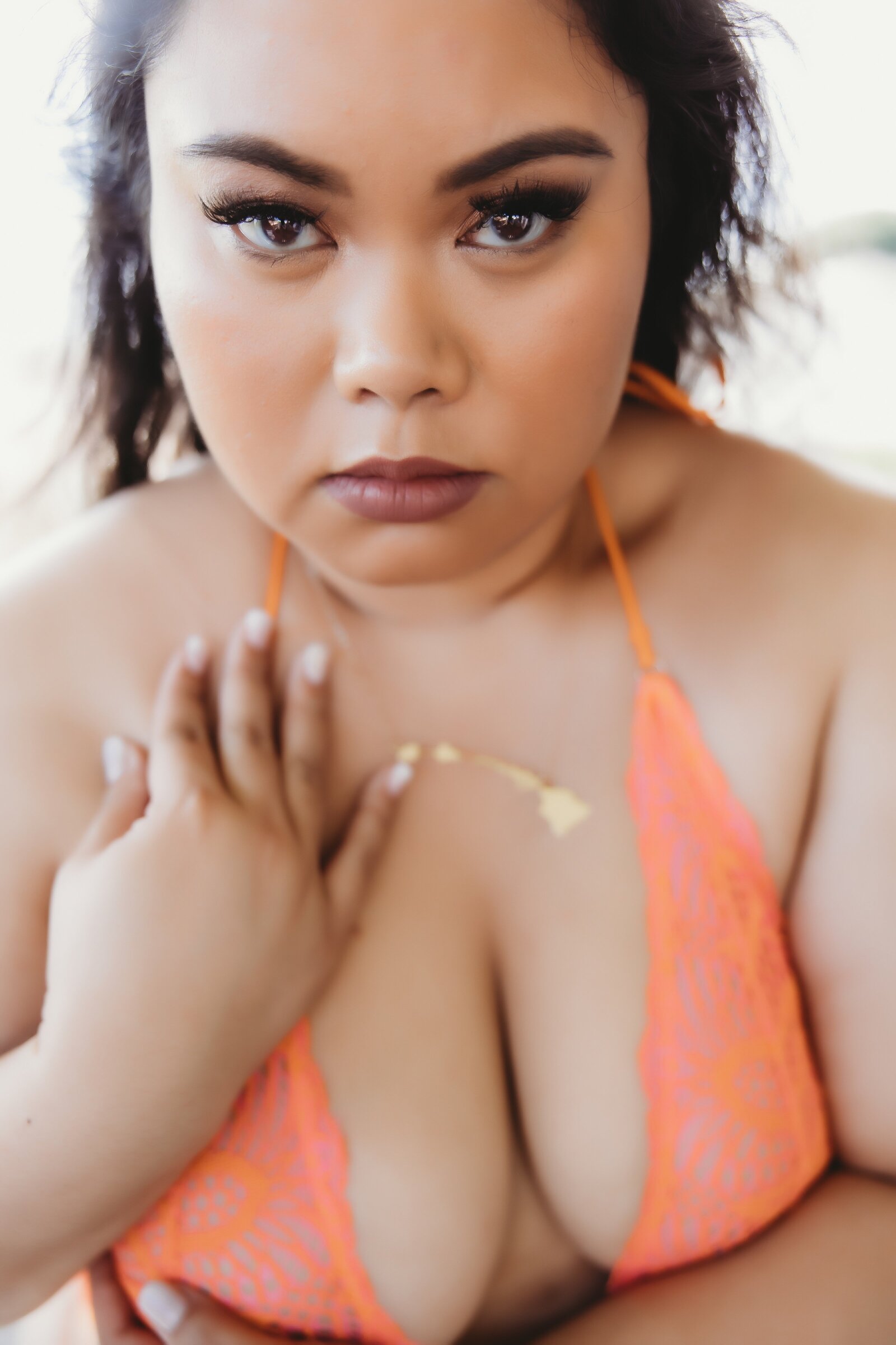 Portrait of woman wearing orange lingerie looking directly into the camera