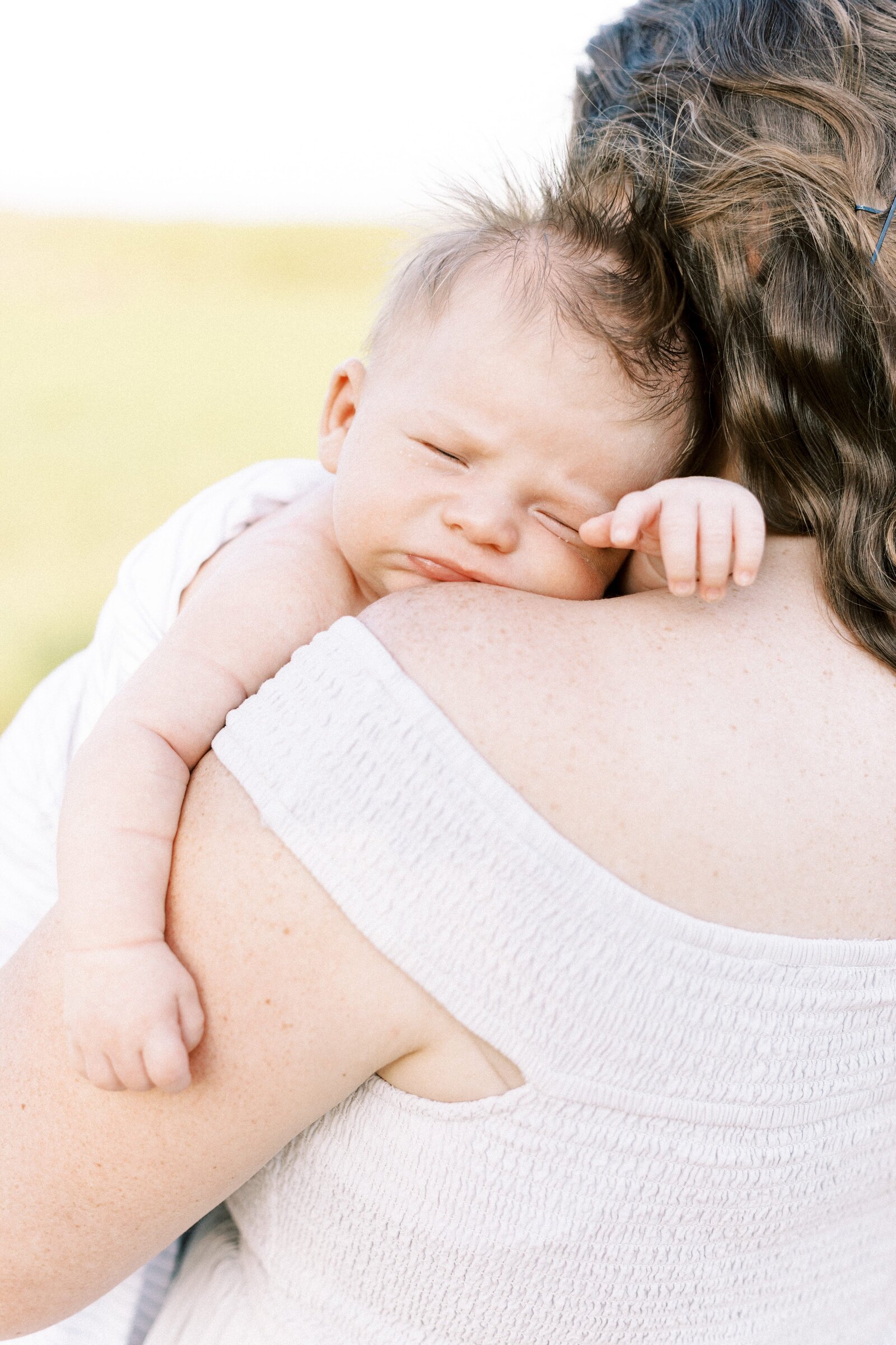 newborn baby looking over mom's shoulder in outdoor newborn photos in peoria illinois 