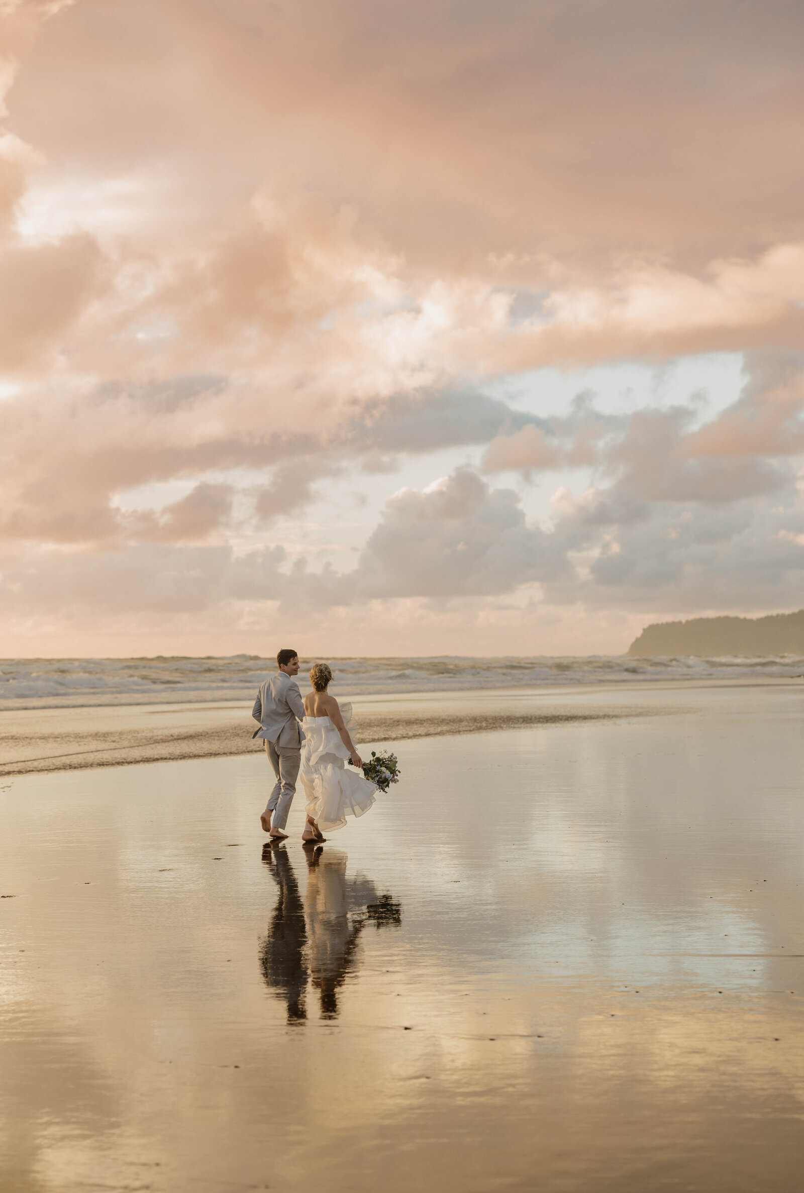 Elopement photographer captures a couple walking hand-in-hand along a picturesque beach, the ocean waves in the background.