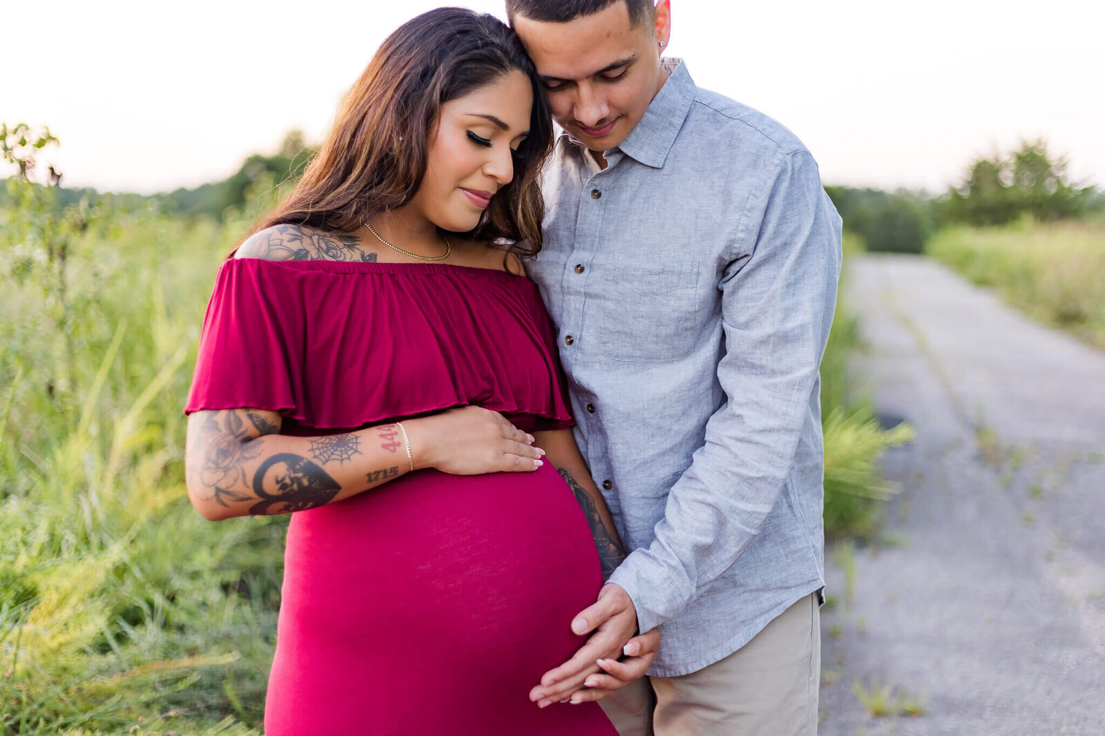 A mom and dad to be holding mom's pregnant belly.