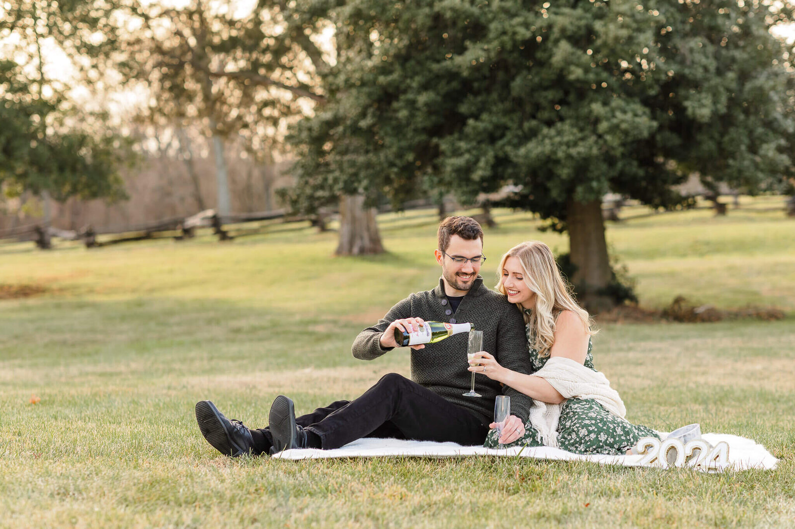 A couple celebrating with sparkling apple cider at a pregnancy announcement session at Sully Historic Site