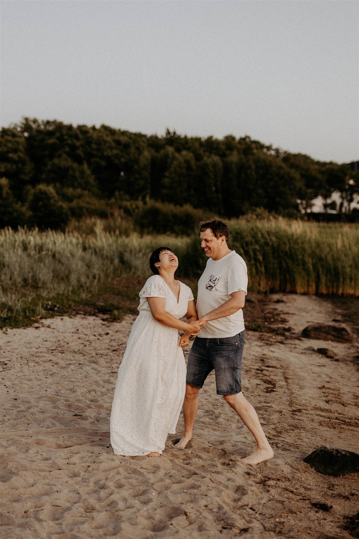 en mamma och pappa gapskrattar hand i hand på en strand