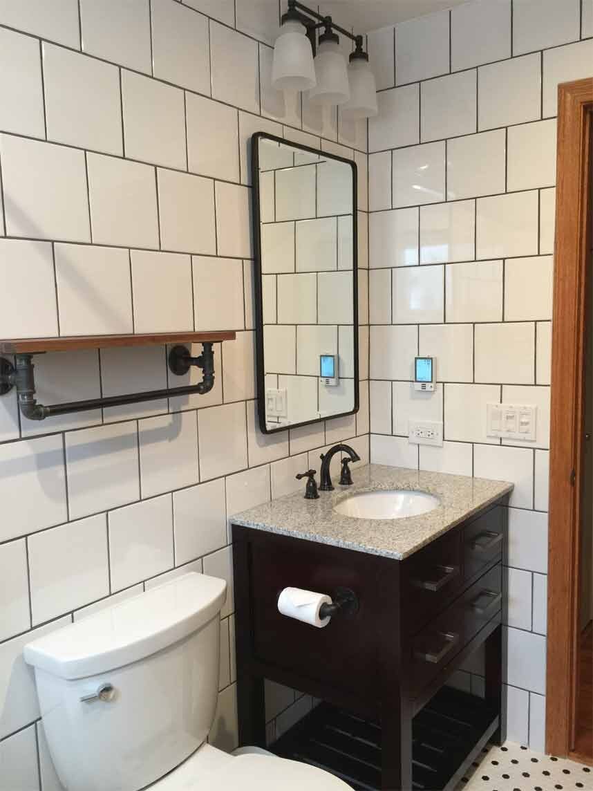Bathroom with white tile and a black sink cabinet
