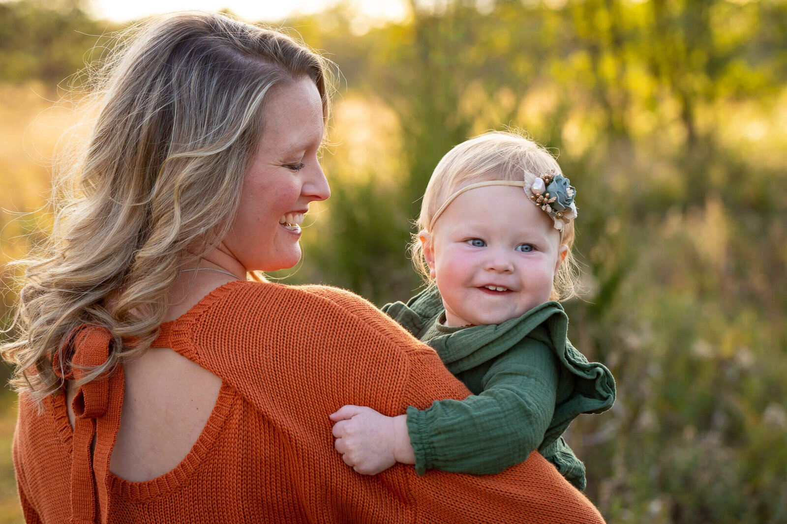 A mom holding her daughter and smiling.