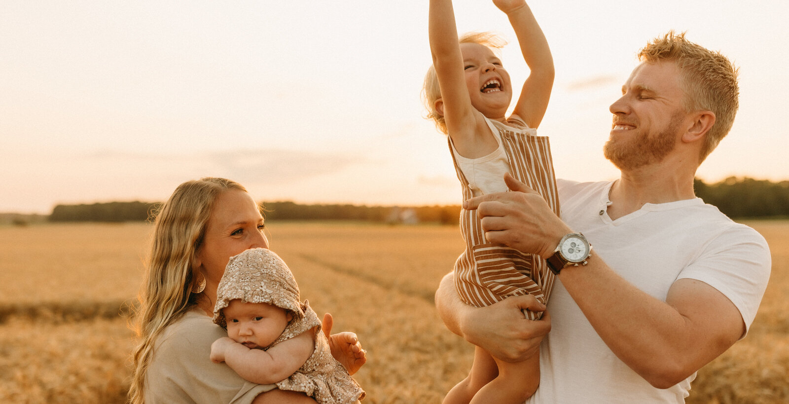 family in wheat field at sunset