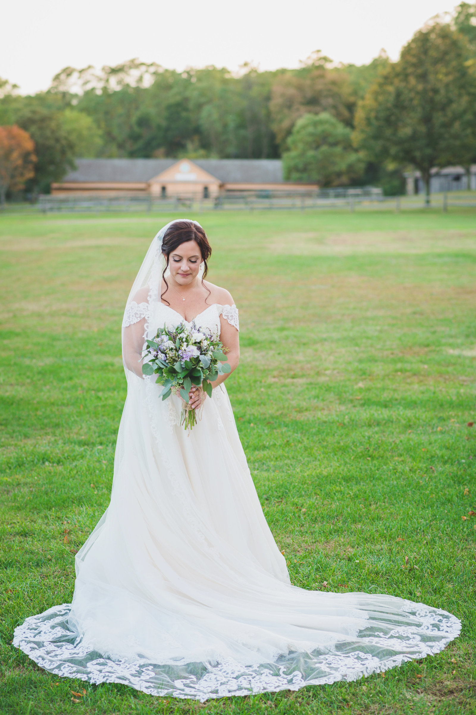 Bride posing looking at her bouquet at The Barn at Old Bethpage