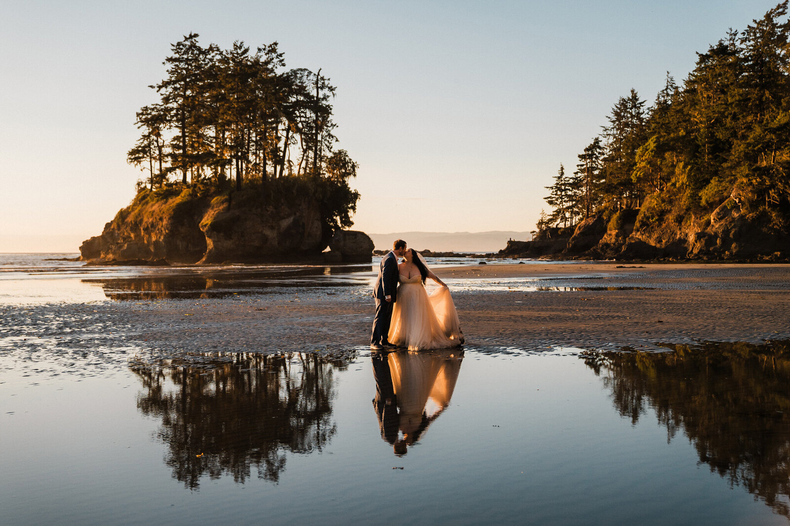 a couple embraces among tall grass with the North Cascades in the background