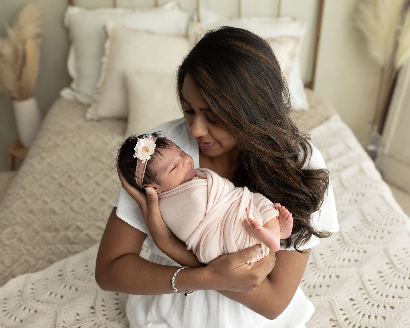 mom holding newborn baby girl wrapped in pink for studio portraits cleveland newborn photographer