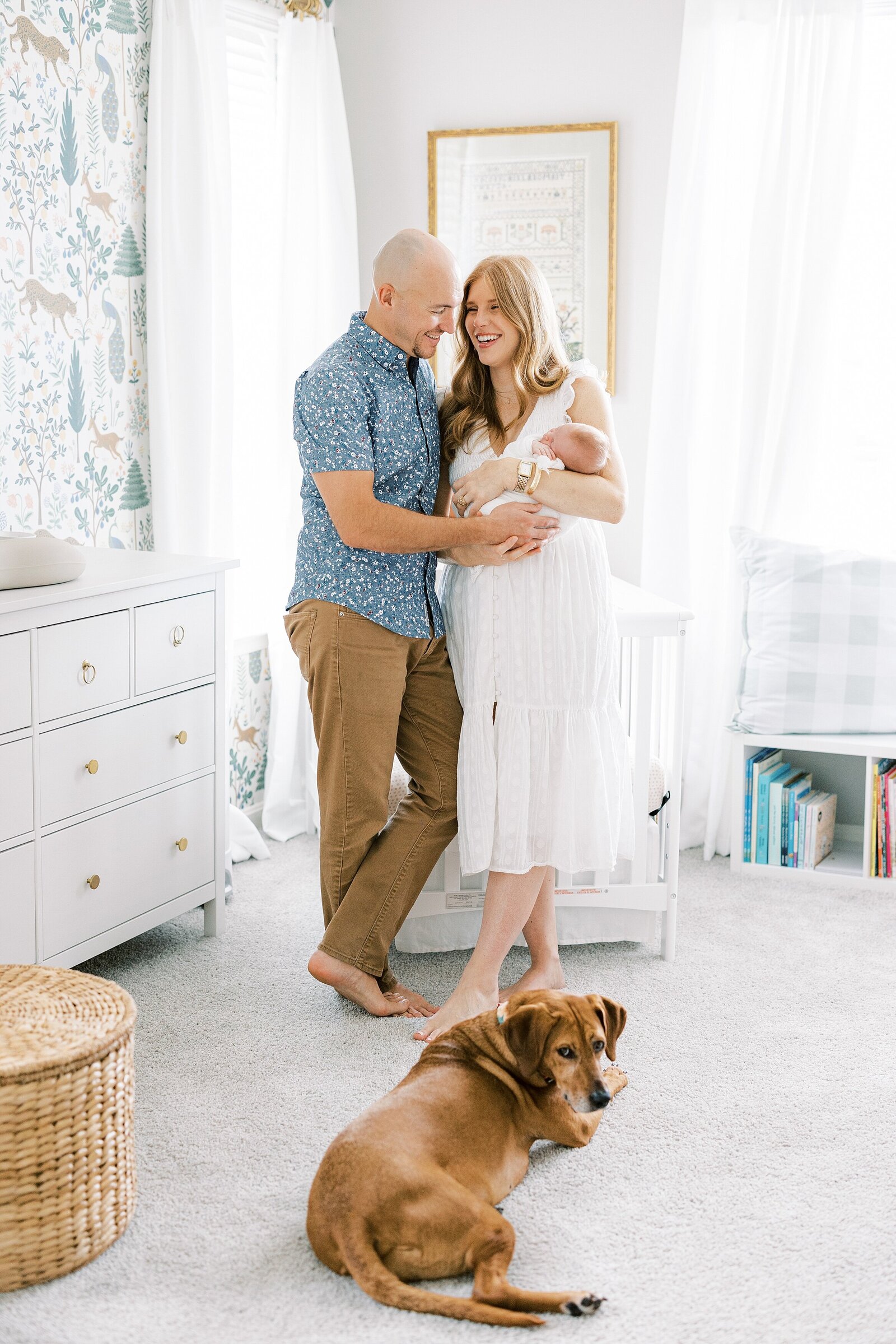 mom and dad holding baby in nursery with dog Newborn Photography West Chester PA