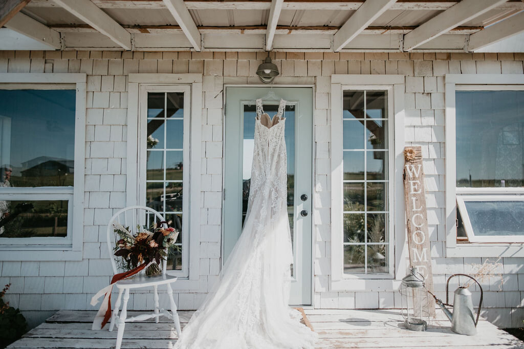 white cottage with blue door, white weddings dress hanging on the door
