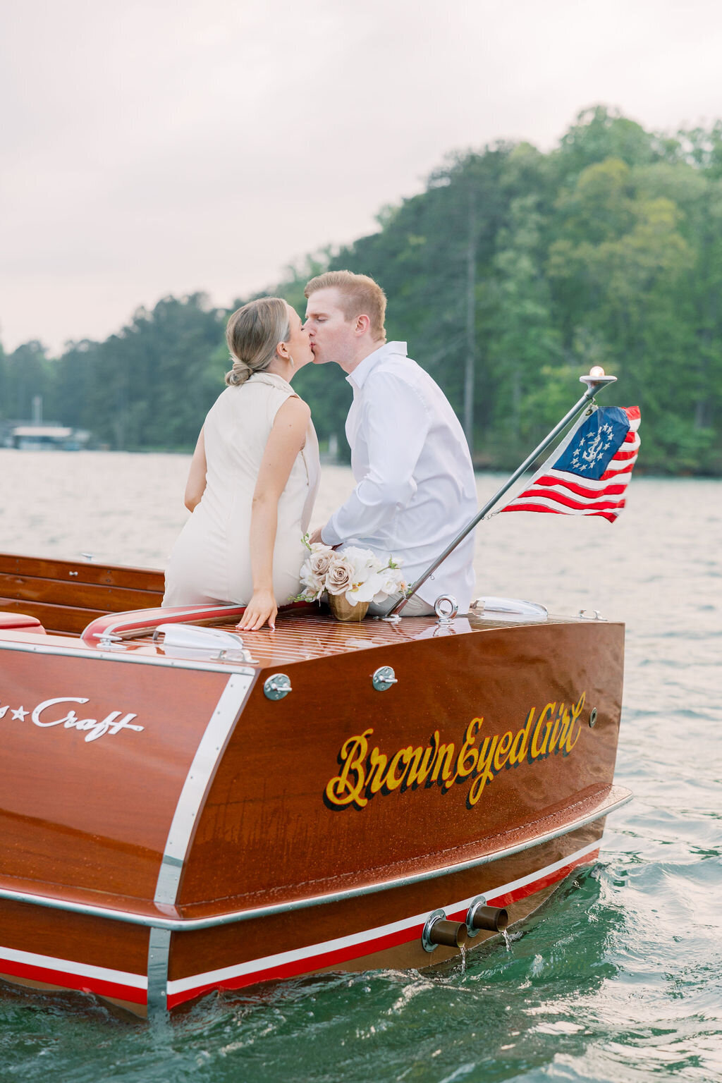 Bride and groom kiss on the back of italian boat on Lake Lanier