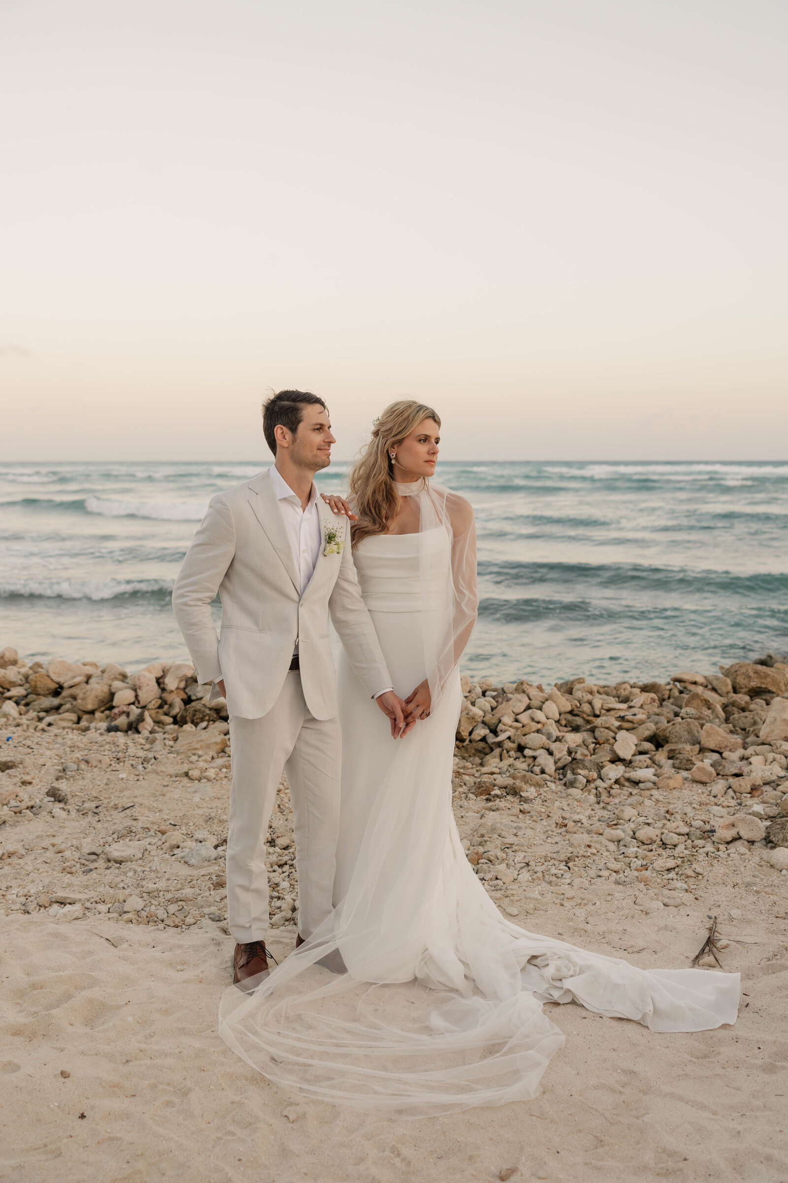 A couple looking out at the beach sunset after an elopement photographer captured their ceremony.