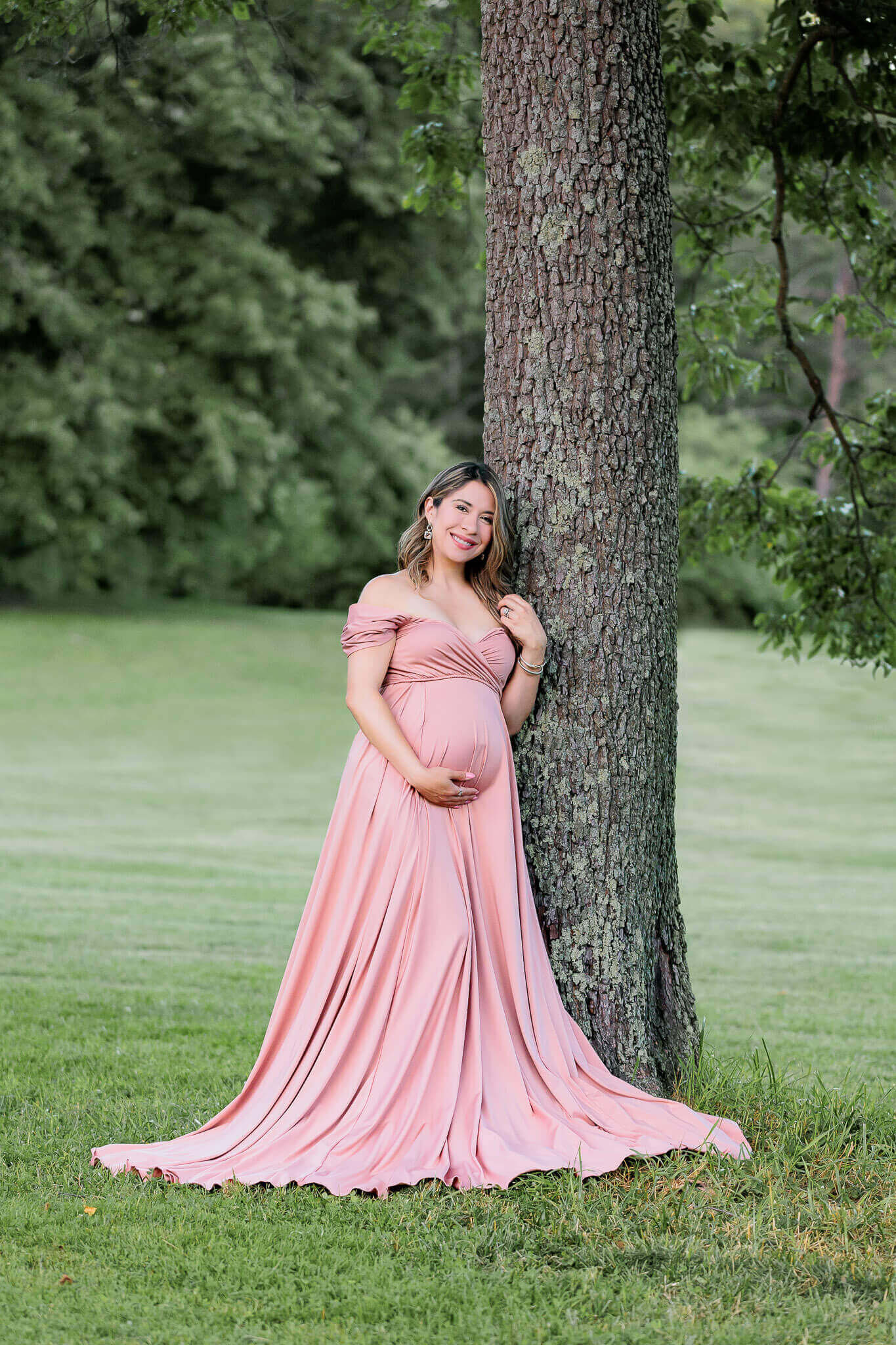 A momma-to-be posing against a tree at a park in Fairfax County.
