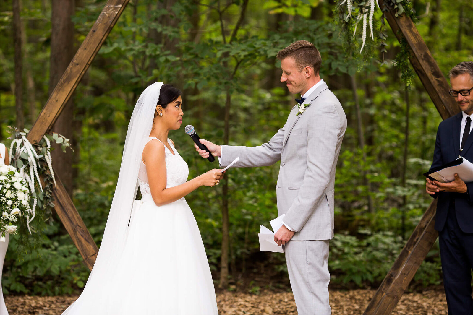 Bride and groom during wedding ceremony at the Clearing Shedden with floral hexagon in background.