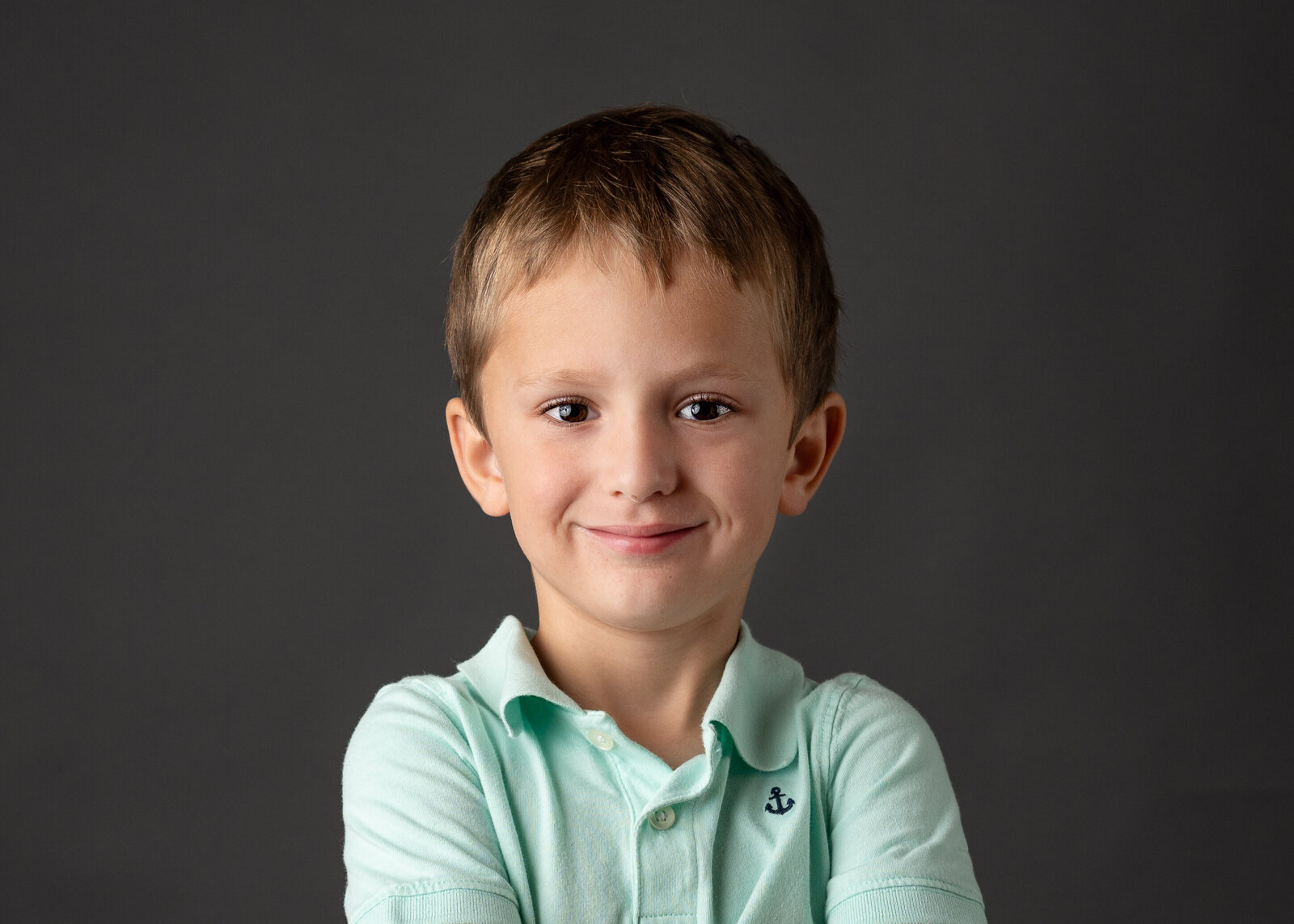 Cheerful young boy wearing mint green shirt with smile for his school picture.