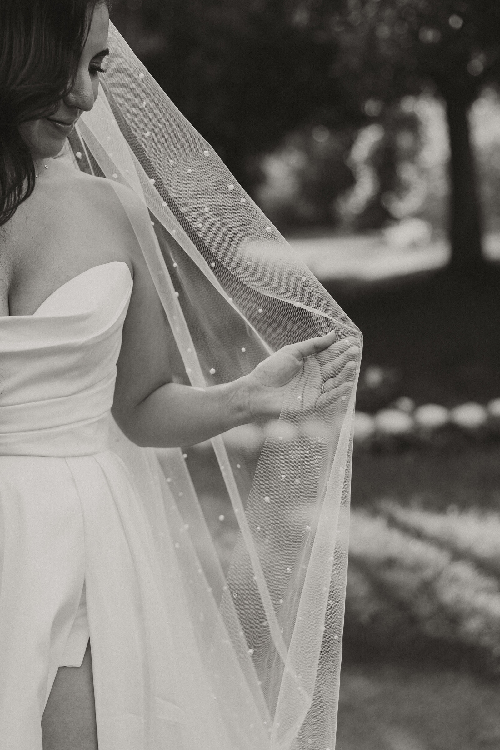 bride holding veil, black and white, slit wedding dress