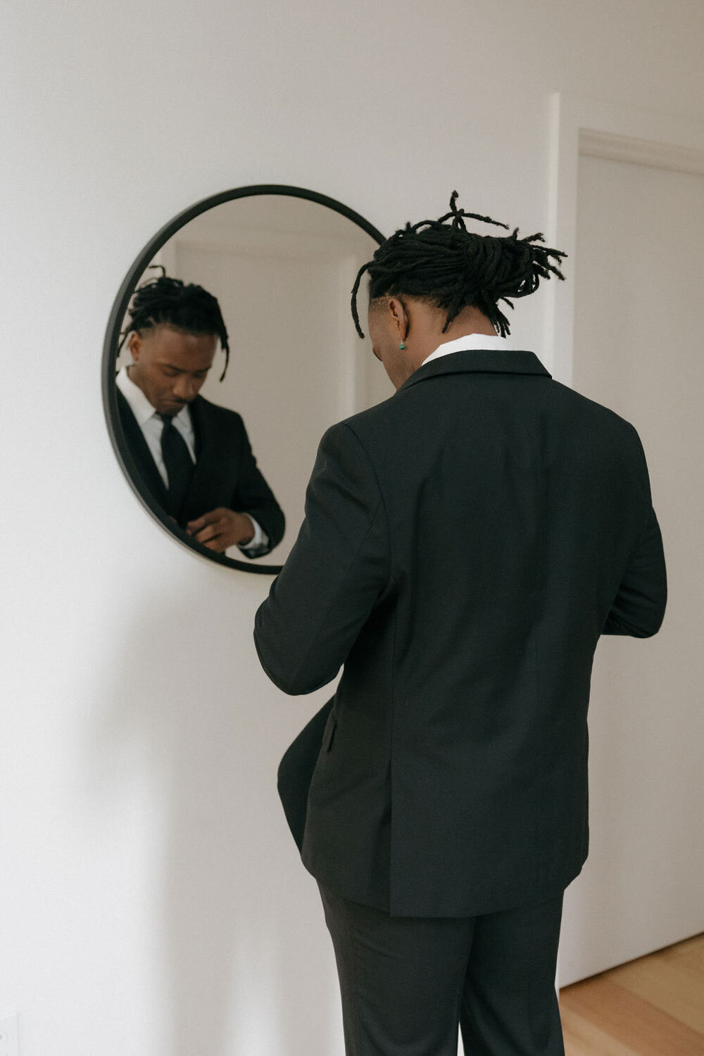 Groom facing a mirror fixing his suit