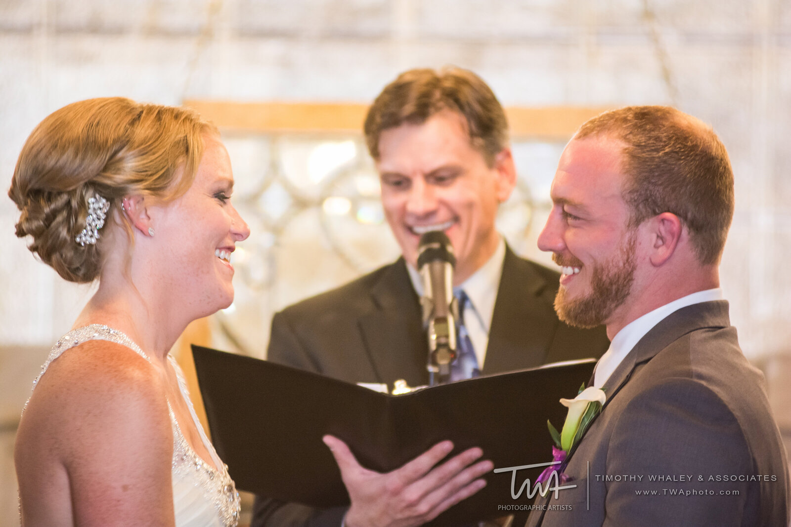Bride, groom, and officiant smile during wedding ceremony