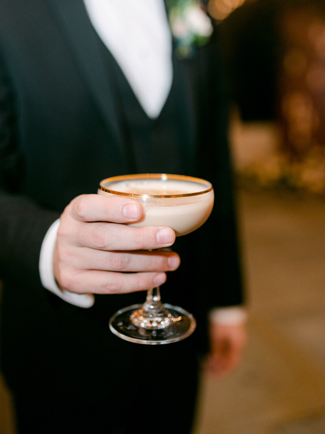 Detail shot of the groom holding an espresso martini.