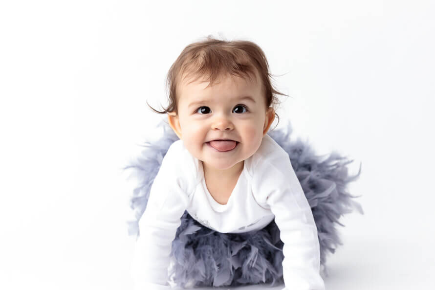 Baby girl in a tutu sticks tongue out for camera during her photo session.