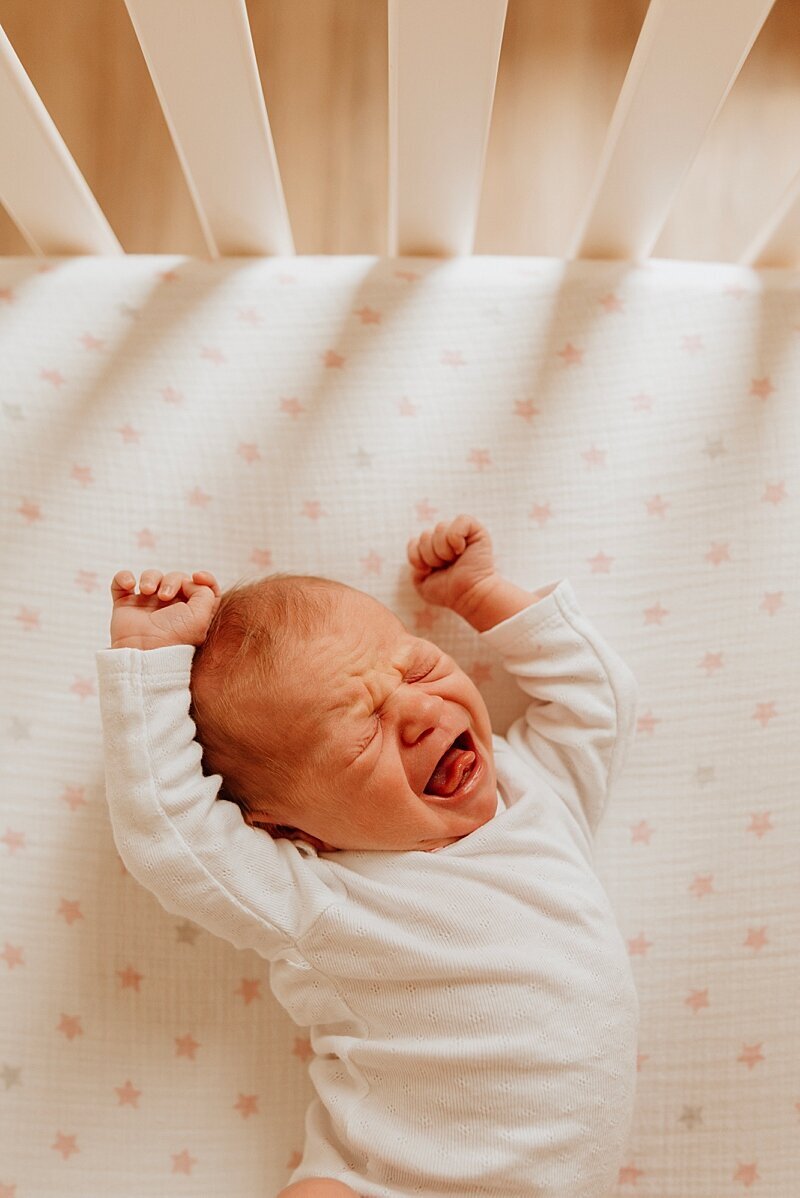 Photo of newborn baby stretching in crib
