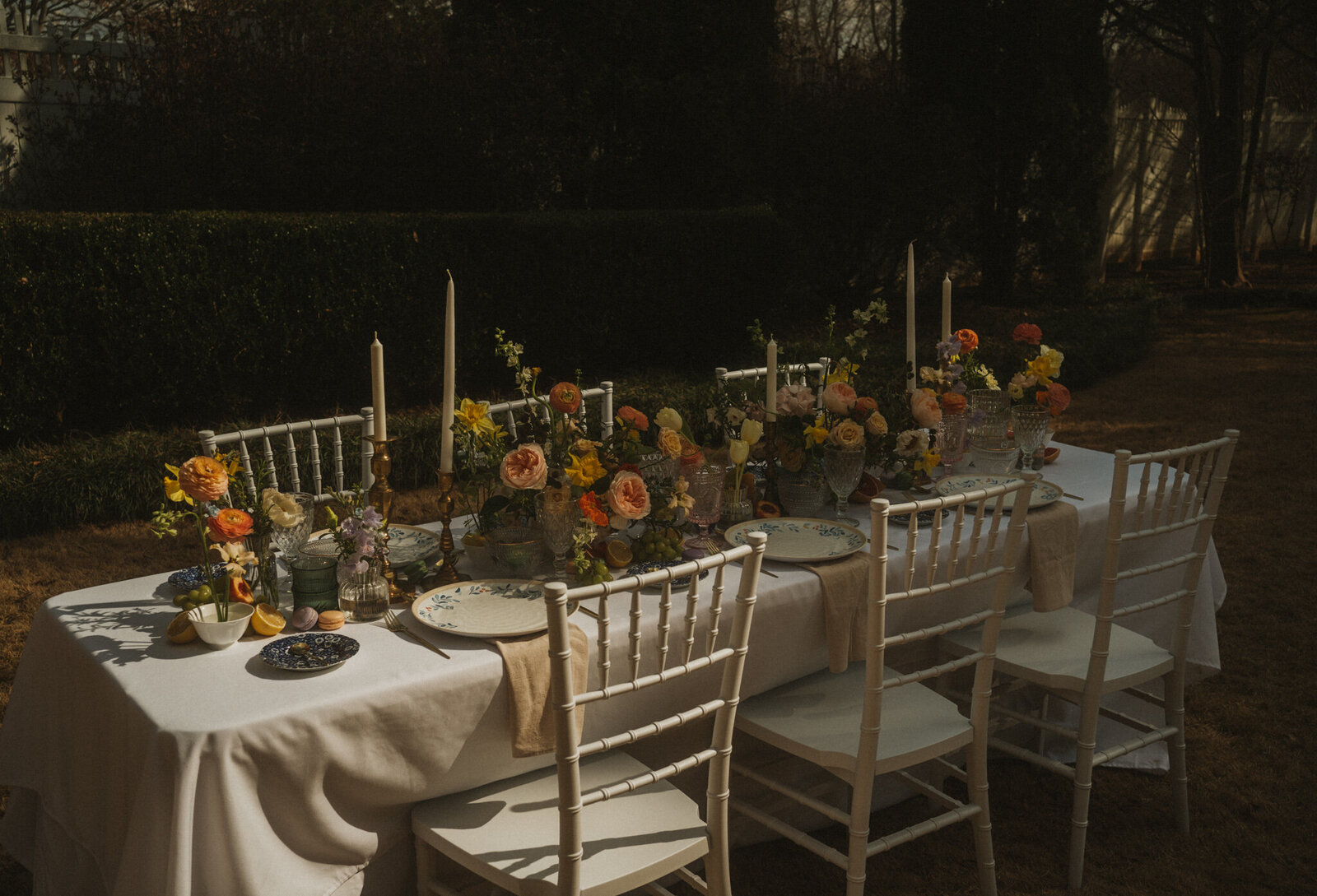 A wedding table at golden hour featuring artistic displays with lots of florals, fruit, and candles in Alabama.