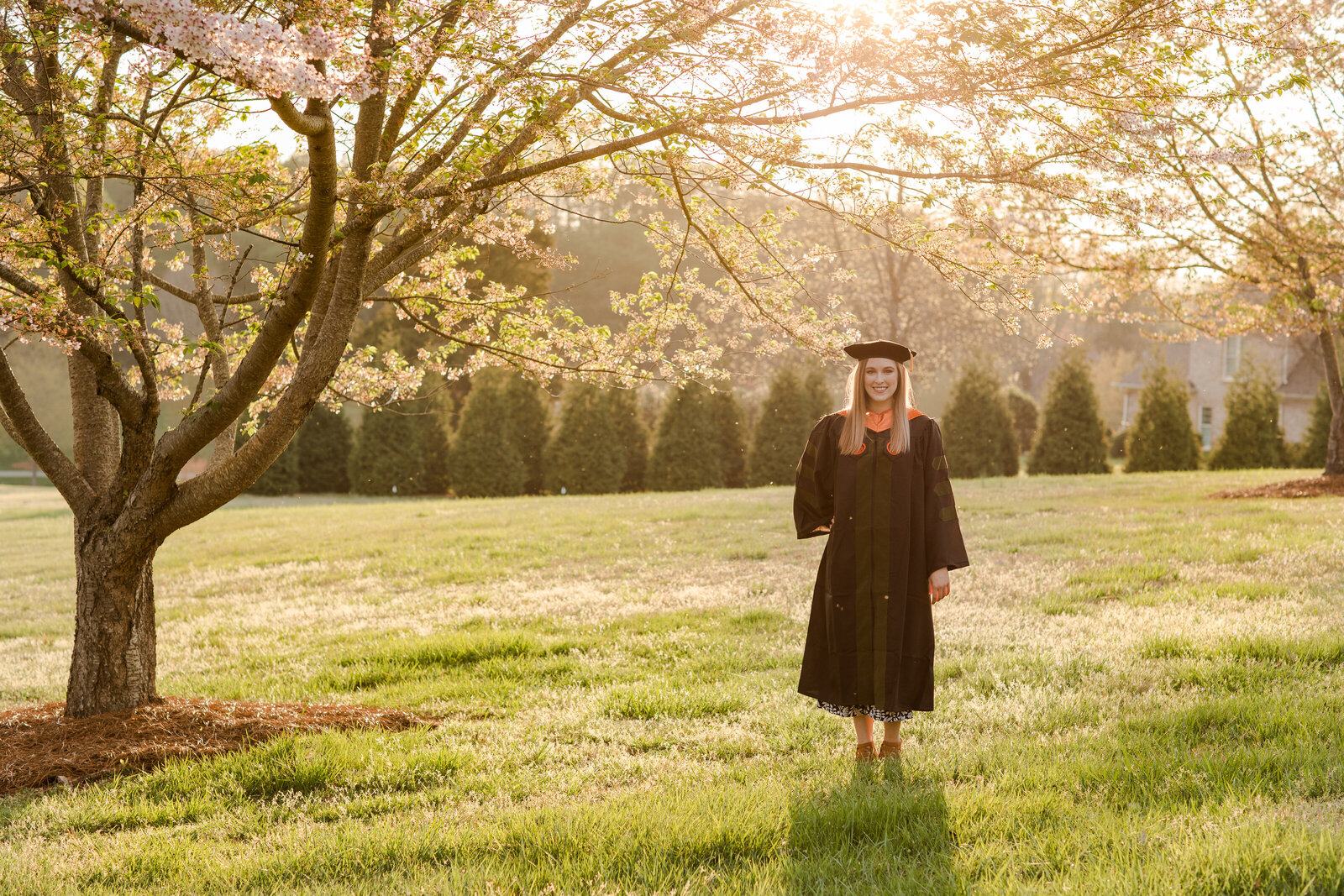 college senior in a field with sunset glow