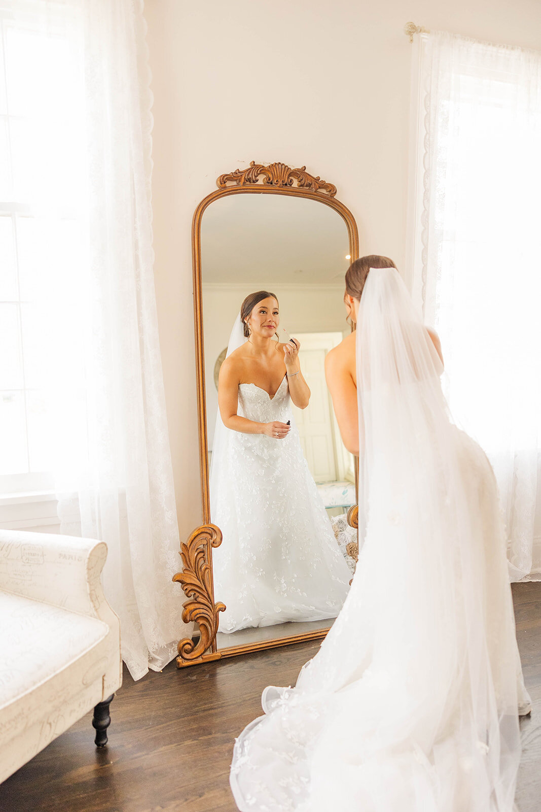 Bride looking in the mirror putting on her lipstick for her wedding ceremony at The Manor House in Littleton, Colorado.