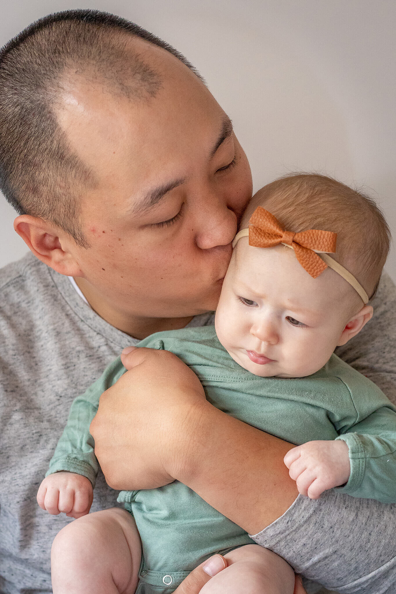 A close-up of a dad kissing his baby's forehead during their session with Northern Virginia newborn photographer, Melissa Driggers.
