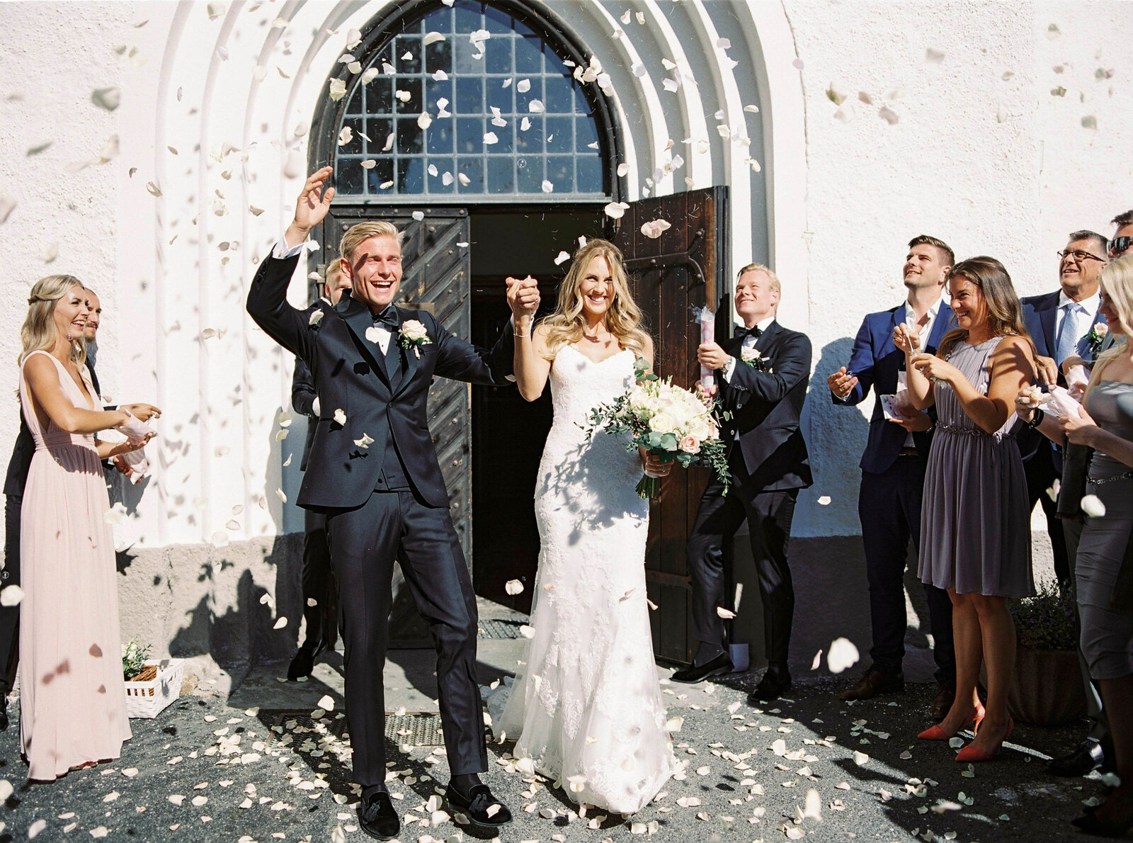 Brides and groom coming out of the church and guests tossing flower petals