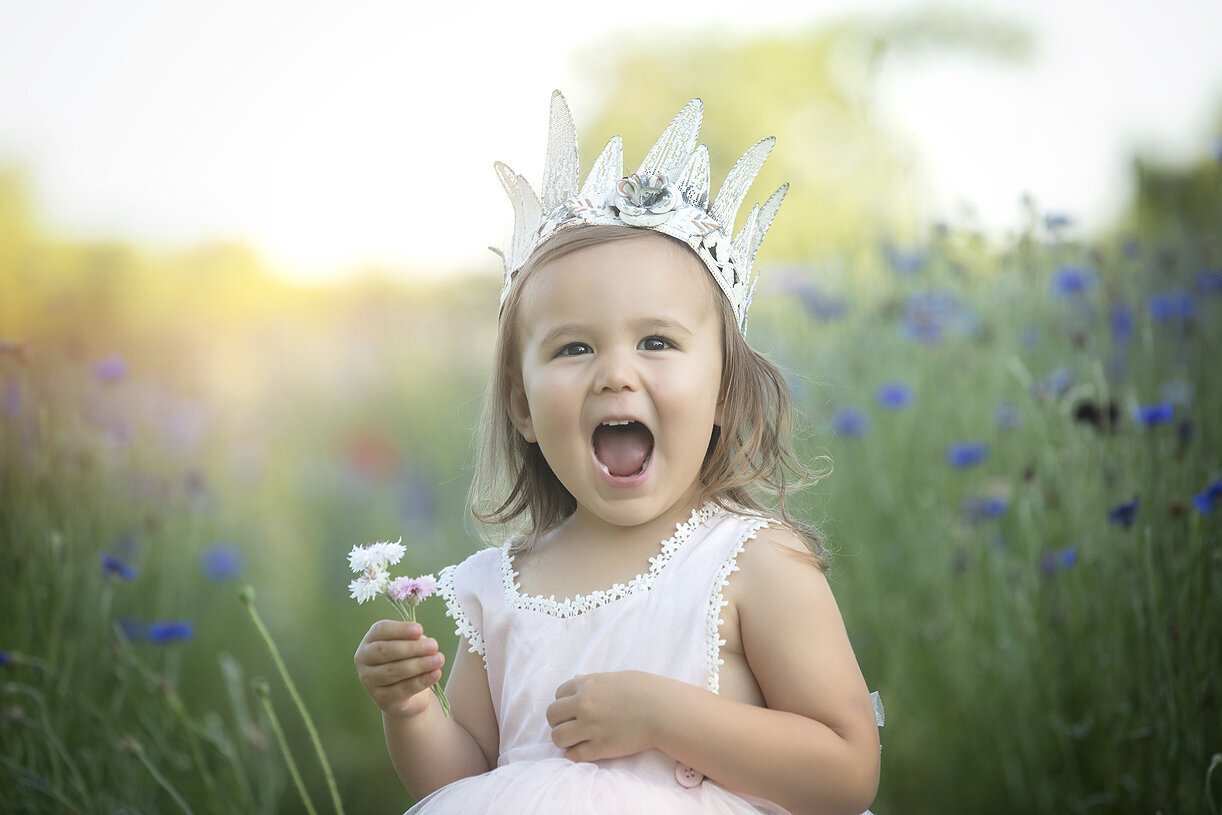 Toddler holding flowers in a flower field.
