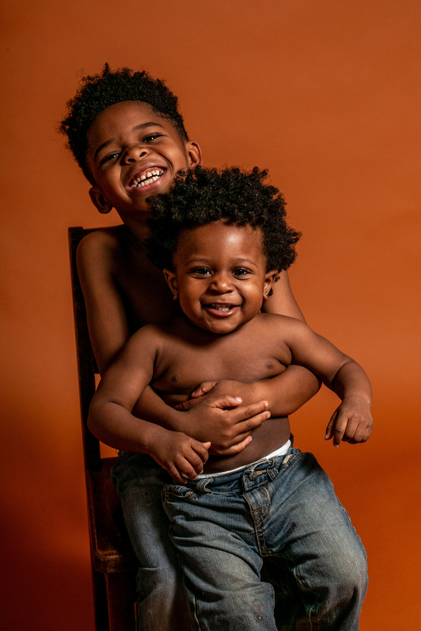 Two African American brothers.Big brother hold his little brother on his lap and they are smiling