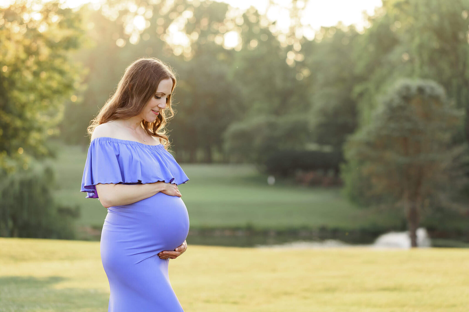 A pregnant mom hugging her belly at a park in Fairfax County, Virginia.