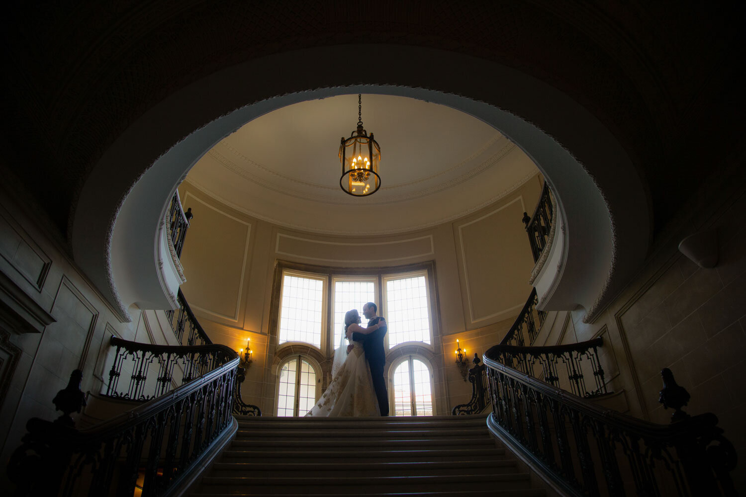 A bride and groom are kissing on a set of stairs