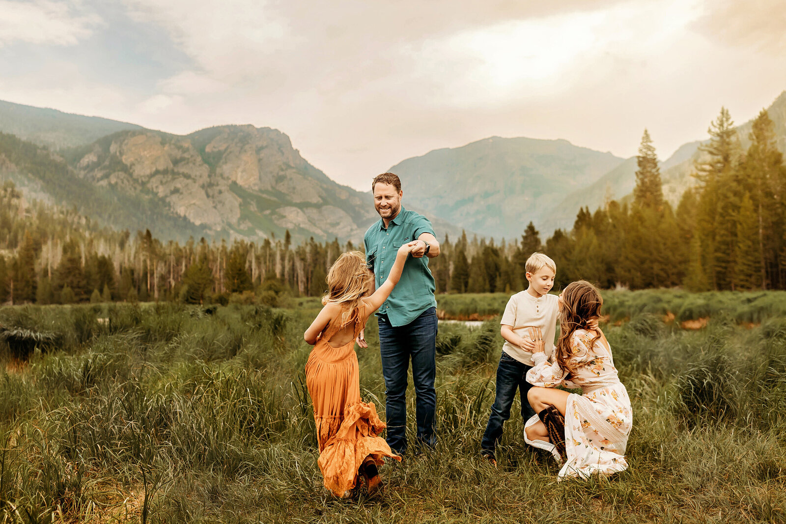 dad twirling young daughter while son hugs mother in the colorado mountains