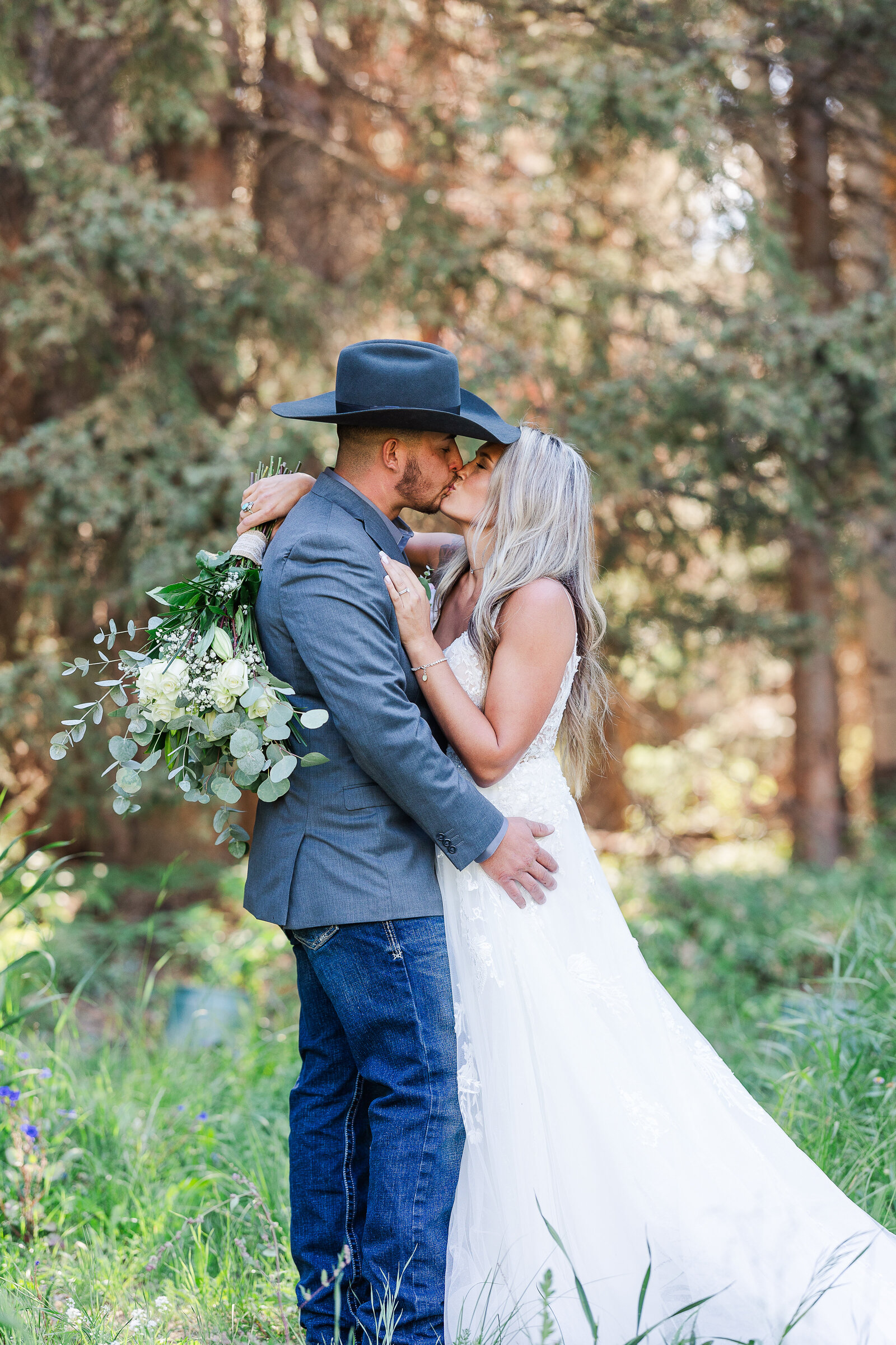 Bride and groom stand chest to chest sharing a kiss with eachother in the flower meadow in arrowhead, co