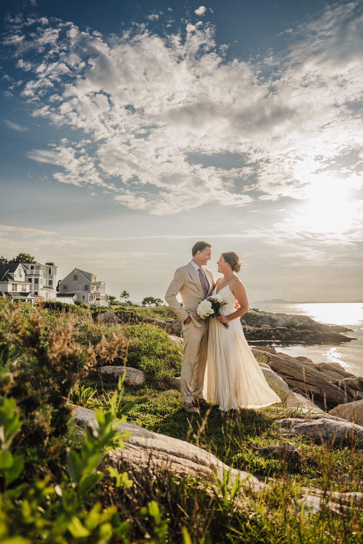 bride and groom look at eachother on rocky cliffs overlooking the ocean in massachusetts
