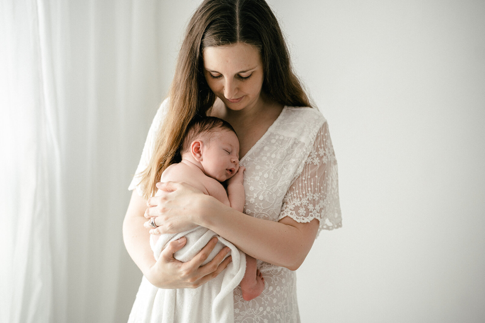 Mother cuddles her newborn baby during her photography photoshoot