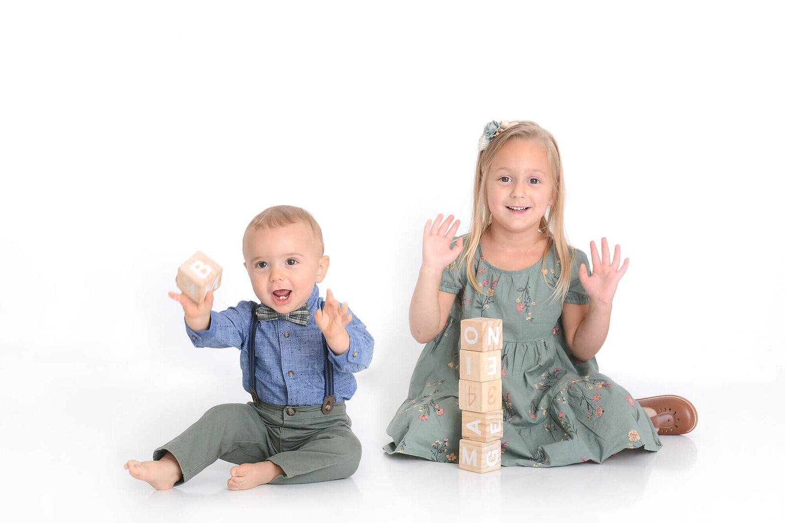 one year old and big sister play with blocks at his first birthday photoshoot