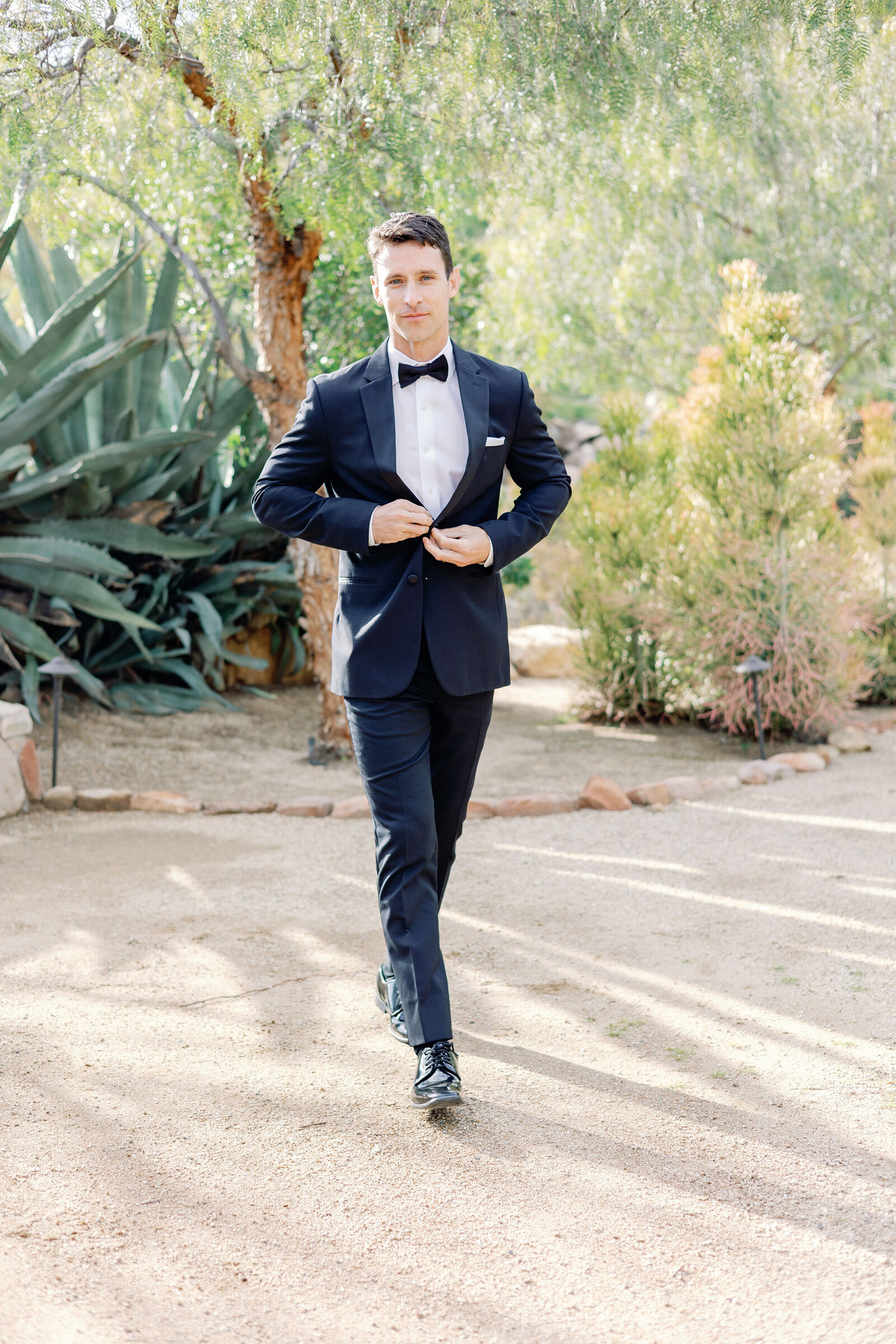 wedding portrait captured by wedding photographer bay area of groom walking outside his wedding venue and buttoning his suit coat