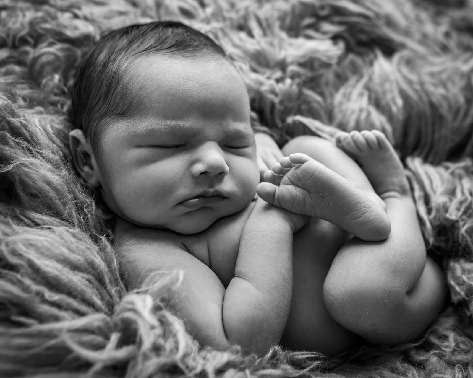 picture of baby curled up on a fuzzy rug