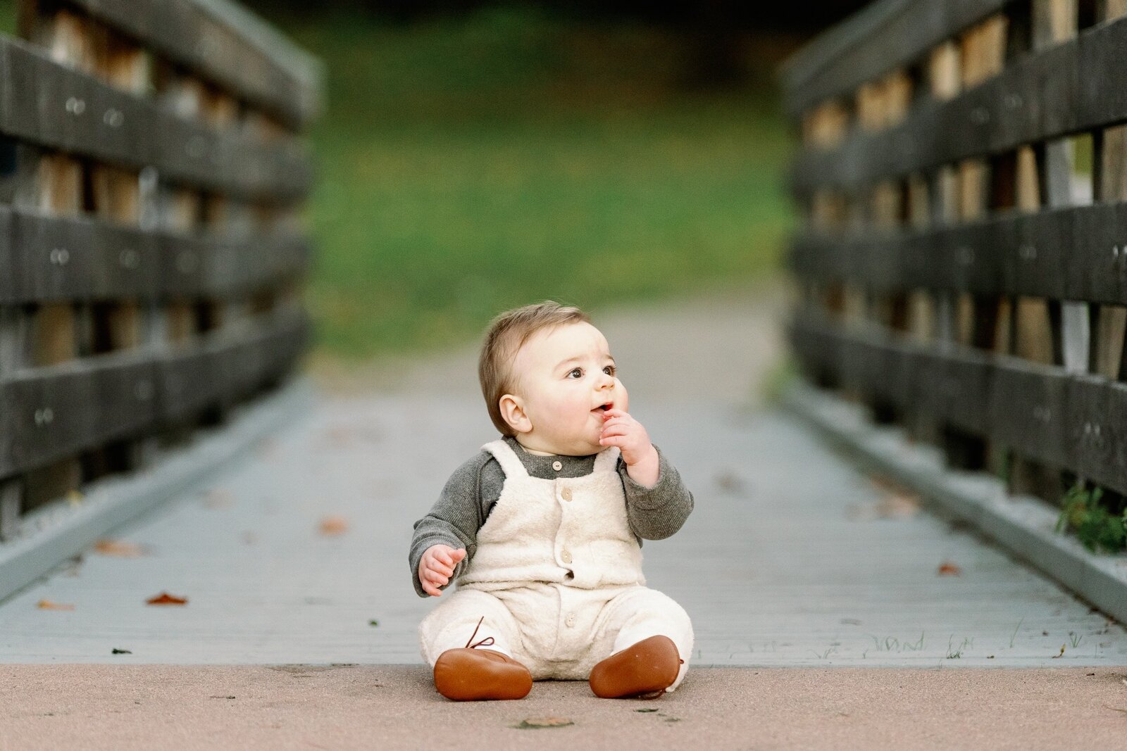 baby in overalls sitting on bridge