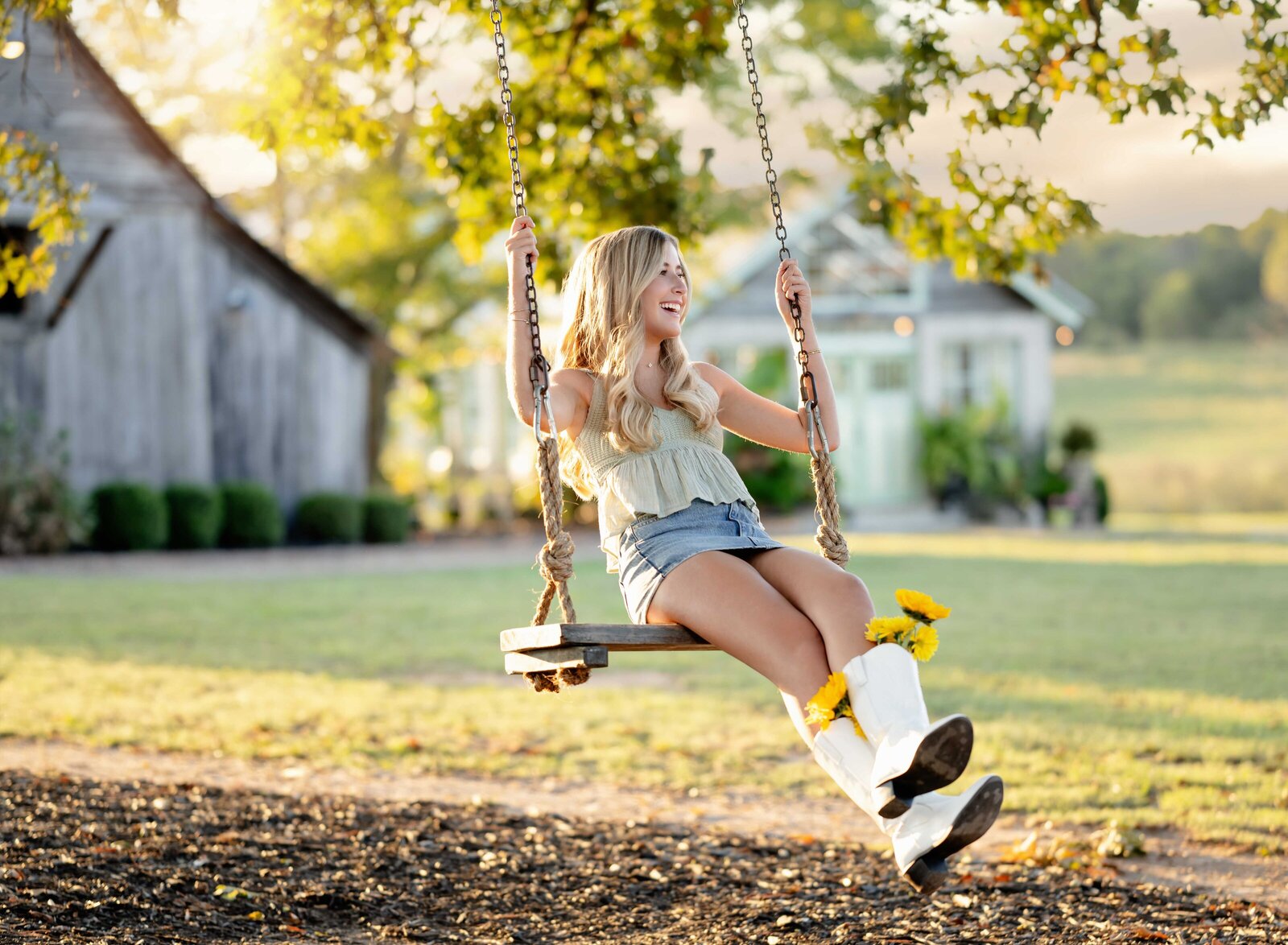Girl graduate winging on tree swing and laughing. Senior graduation photos taken by Jenni Nikki Photography in Atlanta, GA