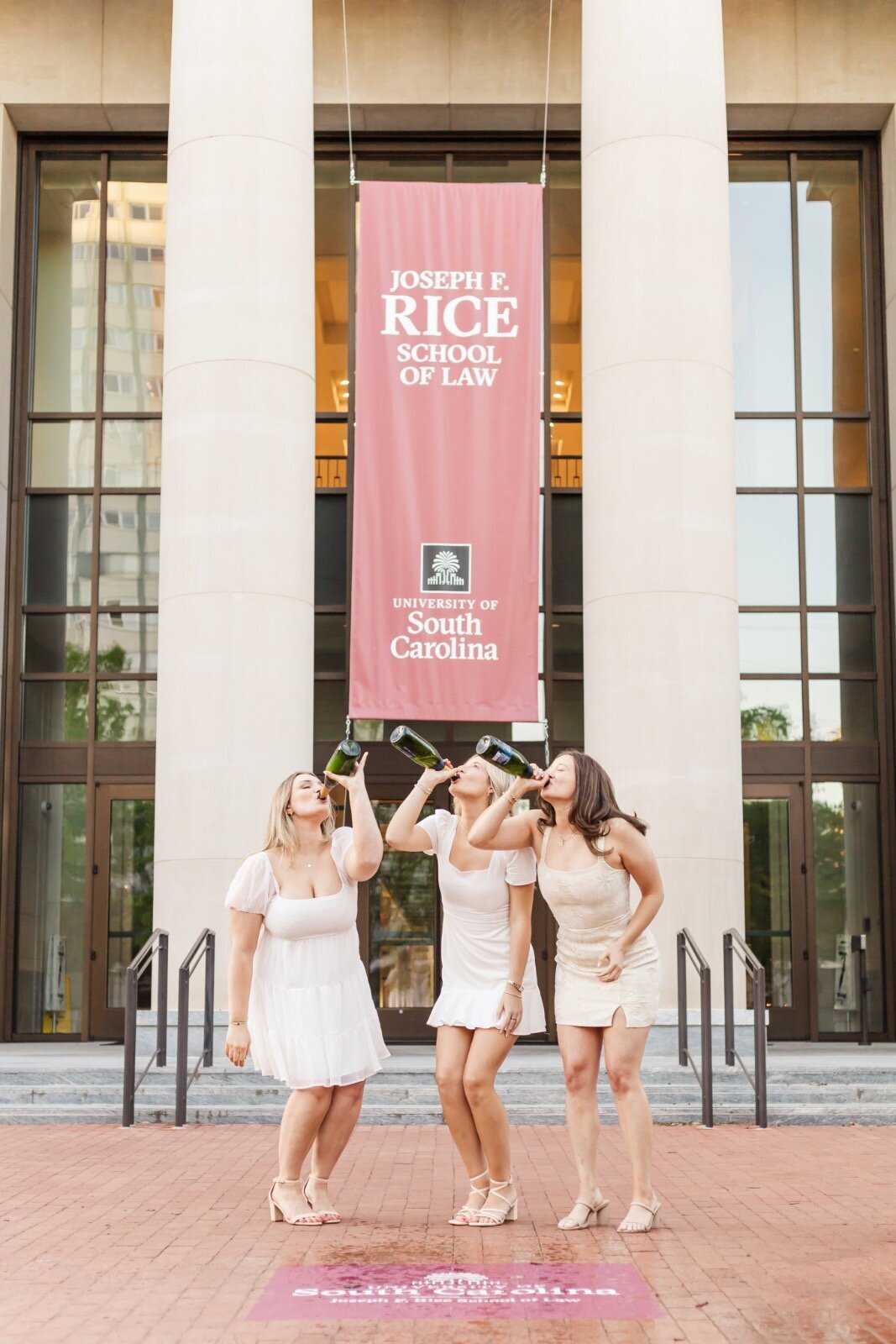 Three girls drinking champagne in front of law school